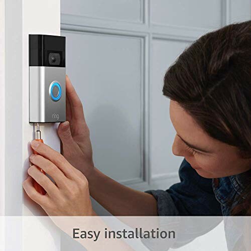 Person installing a video doorbell on a wall.